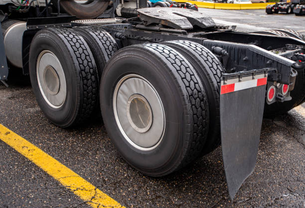 Wheelbase of industrial grade professional big rig freight transportation semi truck with two axles and twin wheels with full tread on them with mud flaps and fifth wheel for coupling of semi trailer